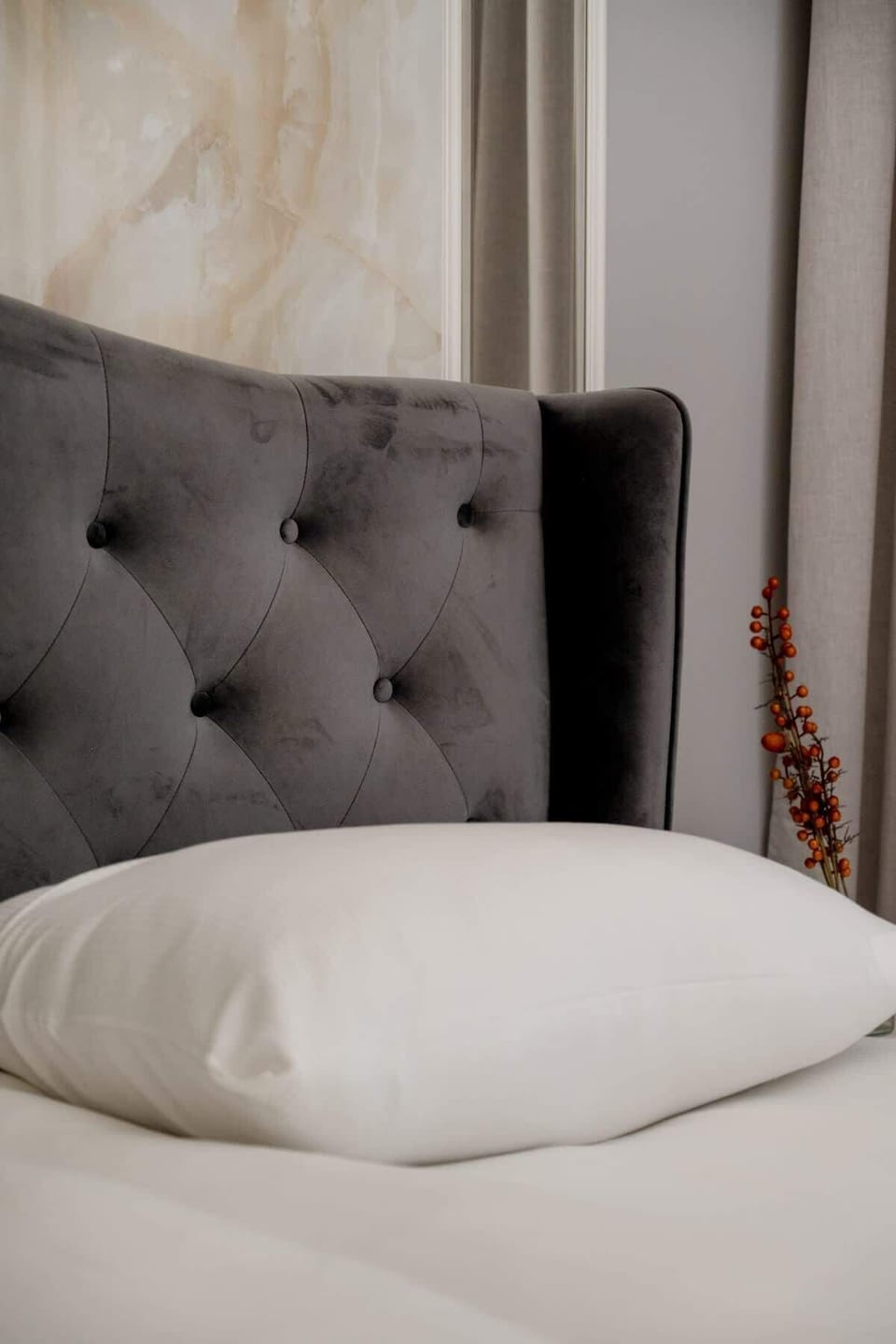 A bedroom with a padded headboard and cozy textures for restful sleep.