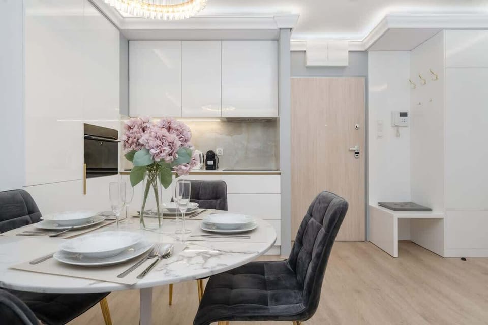 A stylish dining area with a bouquet of flowers and an open kitchen in the background.