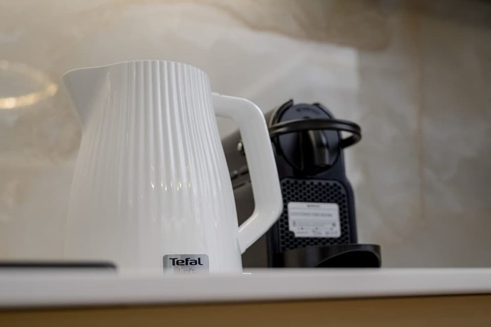A close-up of a white kettle and coffee maker placed on the kitchen counter.