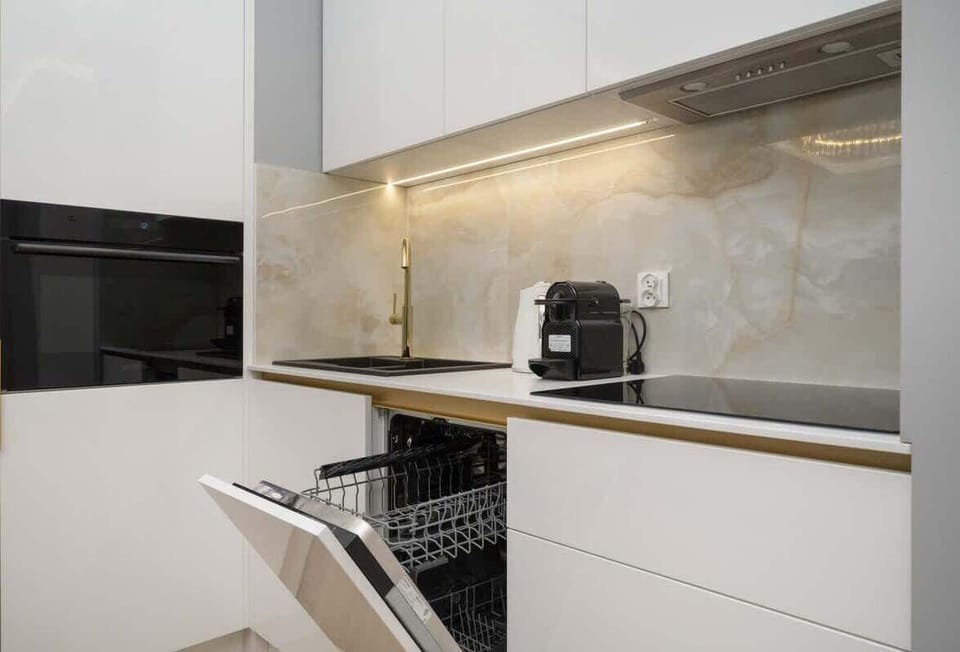 A modern kitchen featuring a stovetop, oven, and sleek backsplash design.