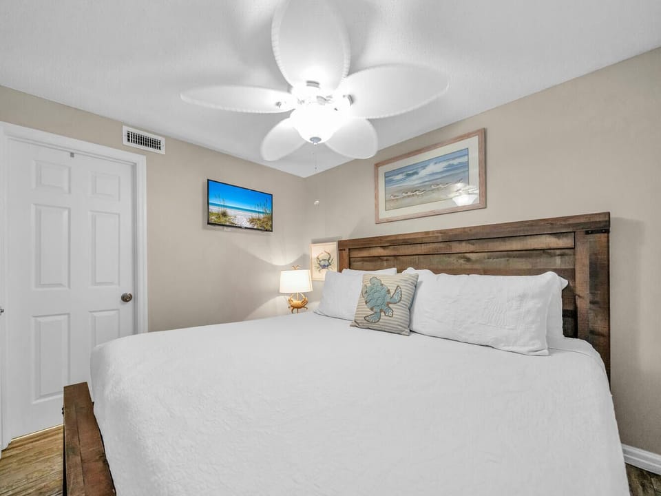 Rest peacefully in your coastal-themed bedroom with rustic wood headboard, crisp linens, and gentle ceiling fan breeze.