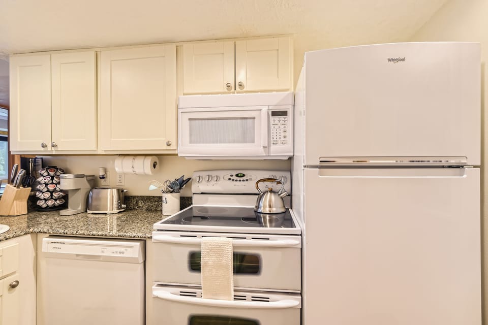 Fully-equipped modern kitchen with granite countertops, electric range, and essential appliances.