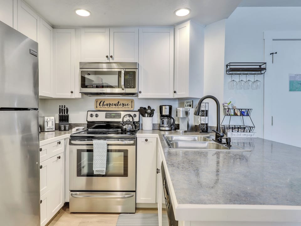 View of the Kitchen Including Microwave, Oven, Stove, Refrigerator, Stainless Steel Sink, Blender, Kettle, Crock Pot, Knife Block