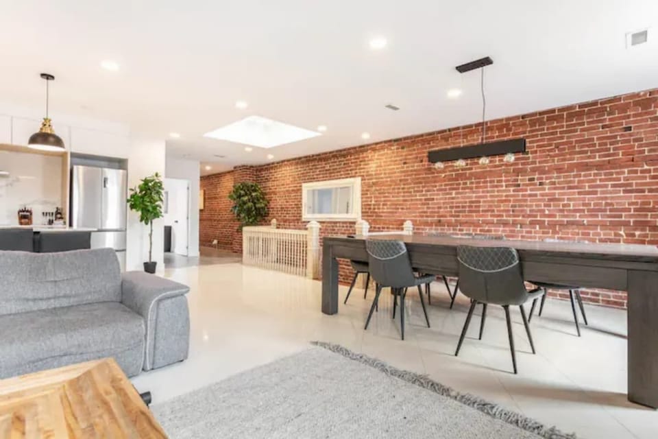 Bright white living area accented by a stylish brick wall for a modern, welcoming vibe.