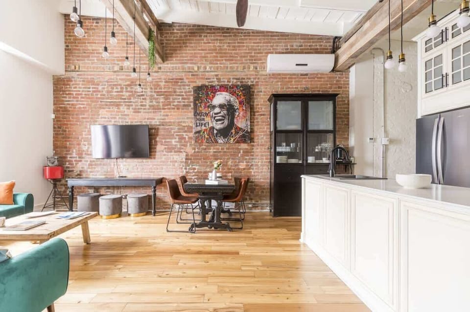 Spacious living area adjacent to the dining space, featuring a rustic brick wall and vinyl flooring that add warmth and character.