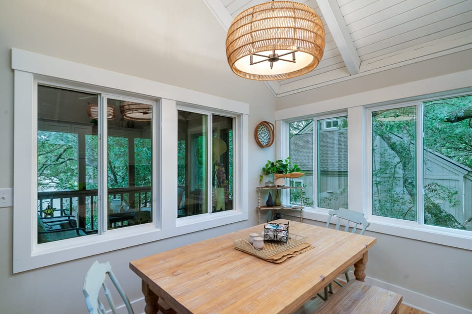 The dining area is surrounded by windows and the beautiful trees of Seabrook Island
