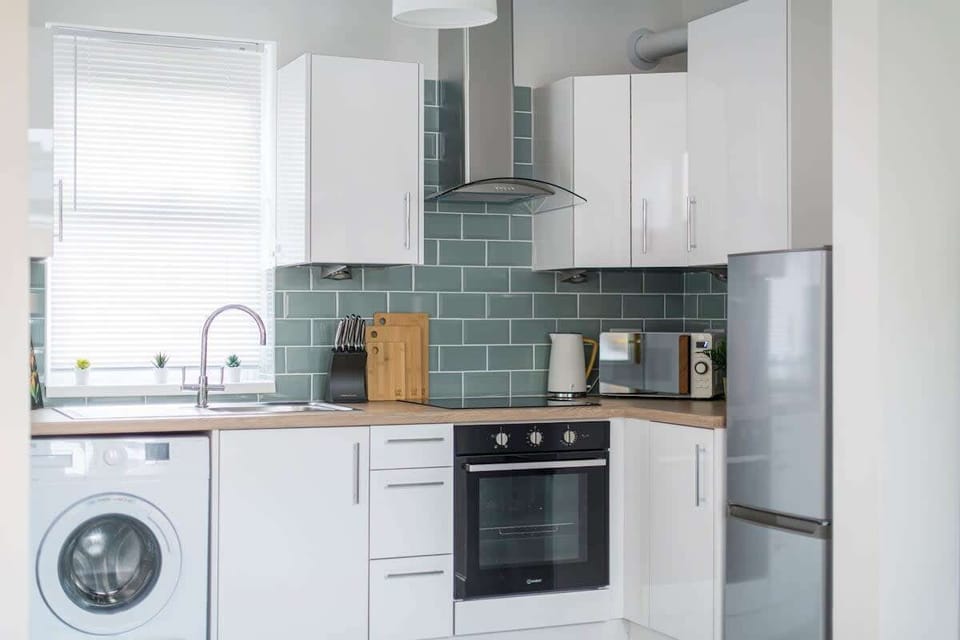 Minimalist and spotless — a clean kitchen area with sleek essentials and a convenient washing machine for a fuss-free stay.