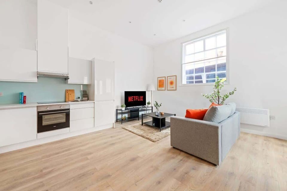 Clean and calming — a relaxing living room featuring a versatile sofa bed and a smart TV, perfect for lounging or an extra cozy sleep space.