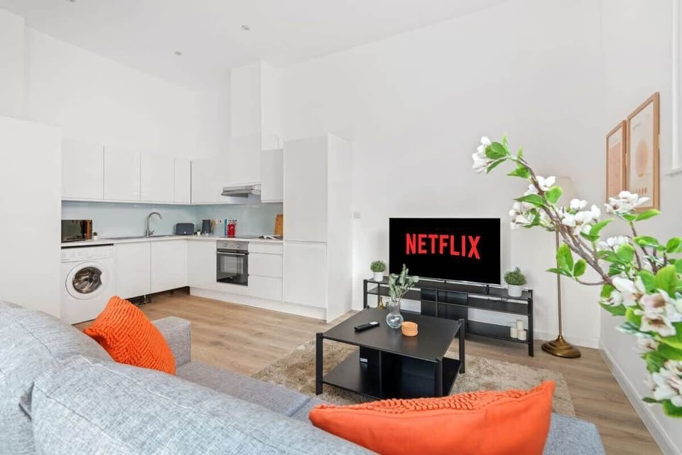 Clean and calming — a relaxing living room featuring a versatile sofa bed and a smart TV, perfect for lounging or an extra cozy sleep space.