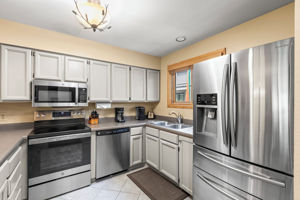 The well-equipped kitchen with grey cabinets and stainless steel appliances.