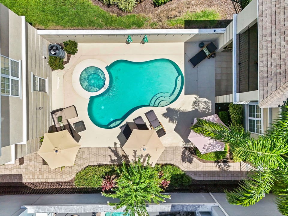 Overhead drone view of the uniquely shaped pool, spa, and patio layout highlighting the private outdoor living space.