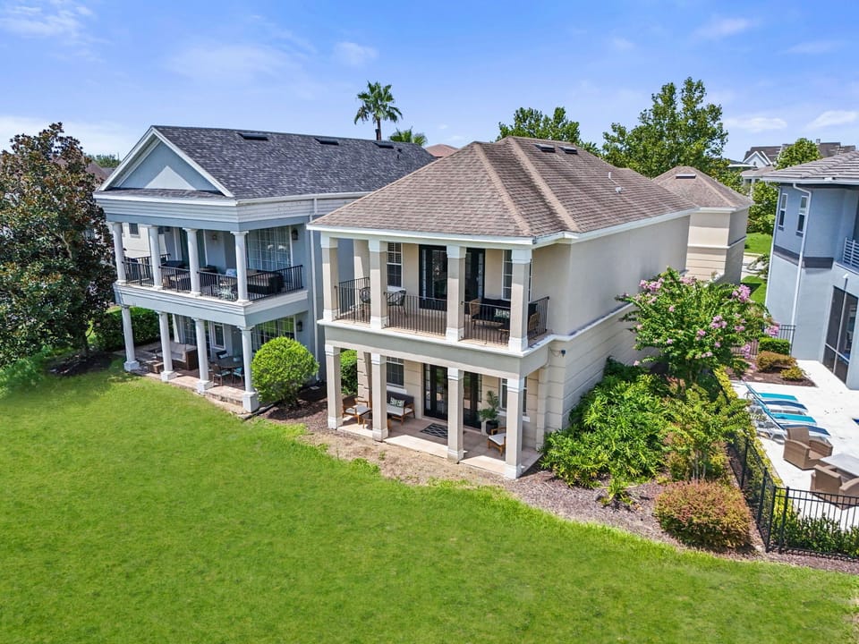 Rear exterior of the home showing expansive lawn space, balcony access, and elegant architectural details.