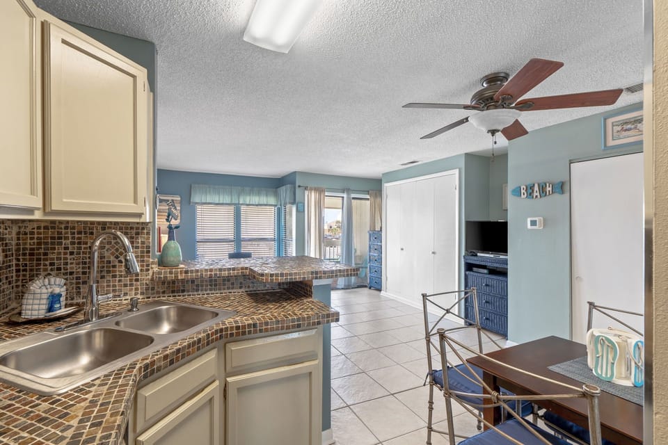 Your beach-themed kitchen welcomes you with charming tile counters and coastal blue walls, perfect for preparing meals after sandy adventures.