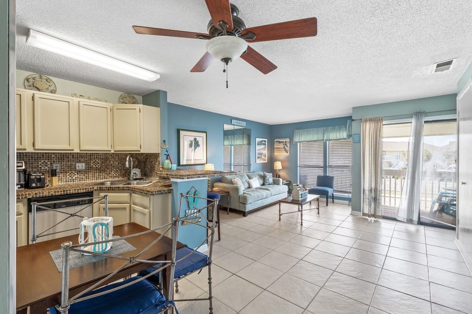 Your open-concept living space blends coastal charm with modern comfort, where the sea-inspired blue walls and fully-equipped kitchen invite relaxation.