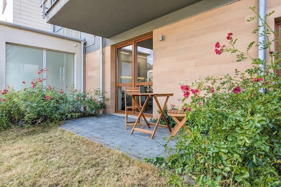 Ground-level terrace with seating, surrounded by greenery and flowers.