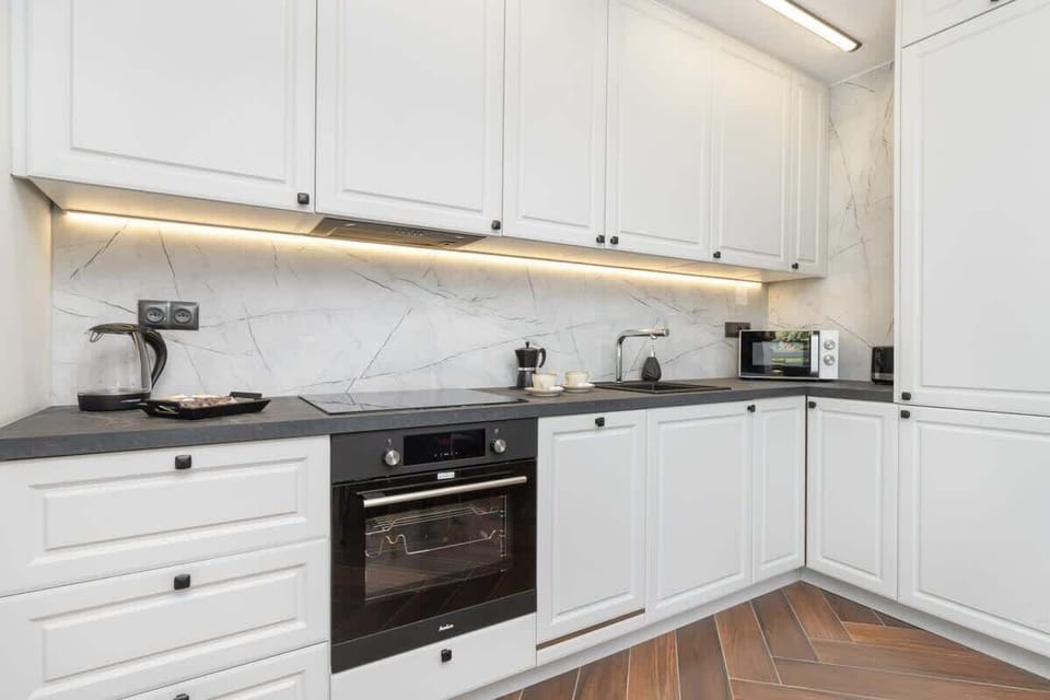 Kitchen – White kitchen cabinetry with built-in oven and modern appliances.


