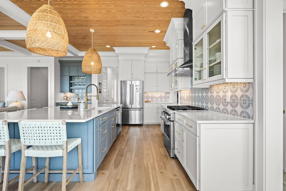Your gourmet kitchen awaits with coastal-inspired blue island, gleaming countertops, and woven pendant lights creating the perfect space for memorable meals.