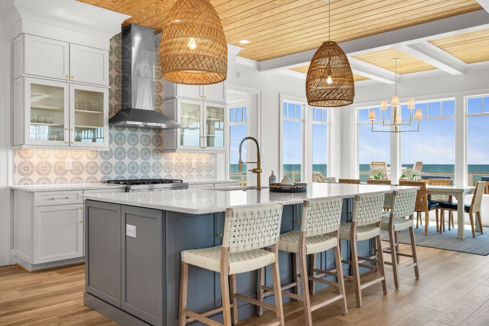 Cook with ocean views in your spacious kitchen featuring a large island, woven pendant lights, and stunning sea vista.