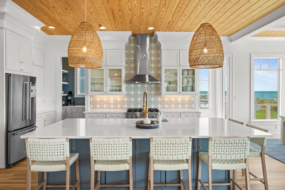 Your stunning kitchen features woven pendant lights and sea views through large windows, creating a serene cooking space.