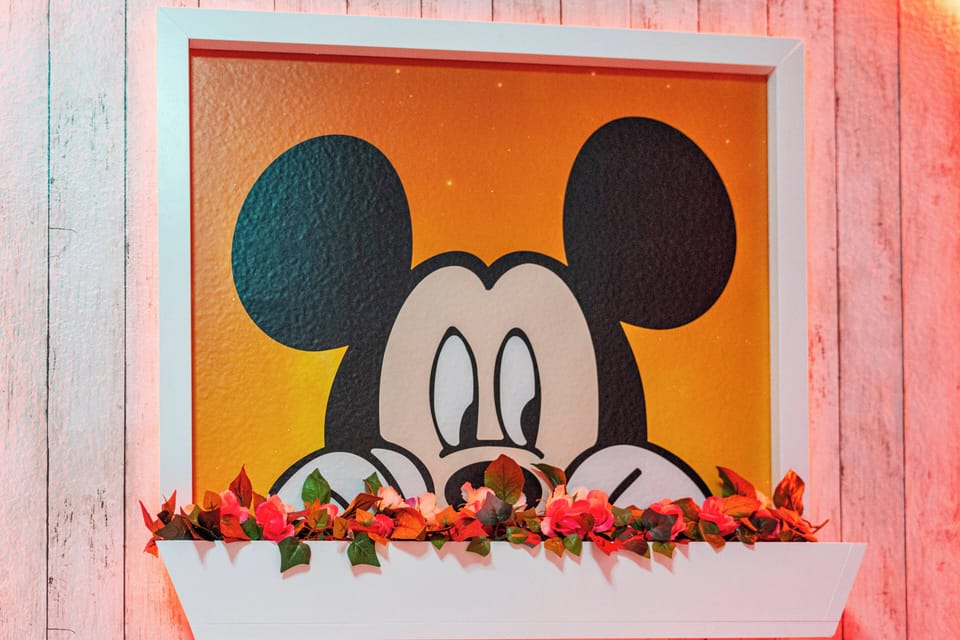 Enhance your stay with this charming artwork of a playful Mickey Mouse, set against a cheerful gradient background. The floral accents add warmth, creating a delightful focal point in your vacation home.