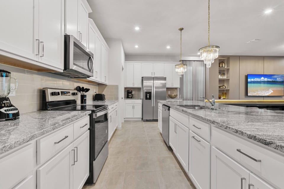 Experience a bright kitchen with sleek white cabinetry and plenty of space for meal prep and gatherings, enhanced by stunning granite countertops and modern stainless steel appliances for style and functionality.