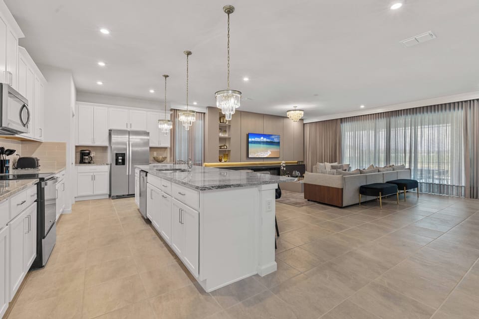 Welcome to a spacious kitchen that perfectly combines style and functionality, featuring sleek white cabinetry, a large island for meal prep or casual dining, warm flooring, modern appliances, and plenty of natural light.