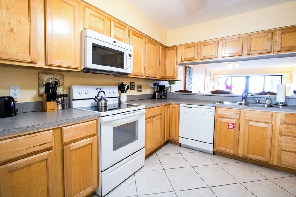 Open kitchen that well-equipped with appliances including a refrigerator, stove, oven, and microwave, making meal preparation. Ample counter space provides plenty of room for cooking and serving.