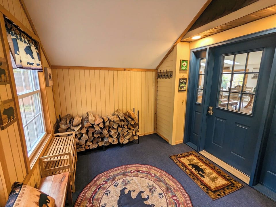 Mudroom stocked with firewood. Perfect for storing skis, snowboards, boots. 