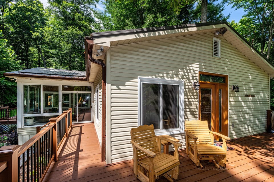 Wooden deck with two natural wood rocking chairs and a small matching side table by a beige vinyl house.