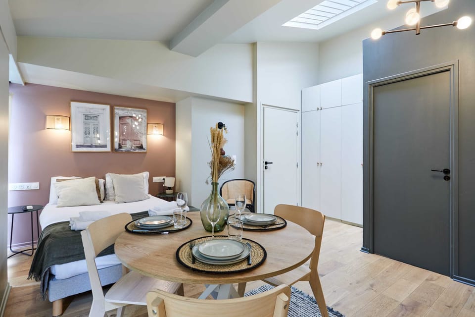 Grand studio avec lit double, un canapé lit simple, TV, coin repas et cuisine ouverte équipée.