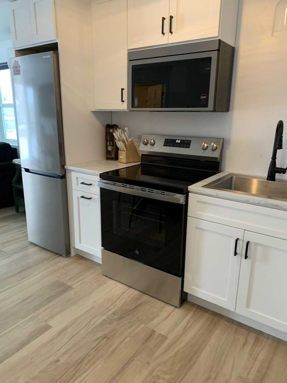 Full kitchen with overhead microwave, small fridge and dishwasher.