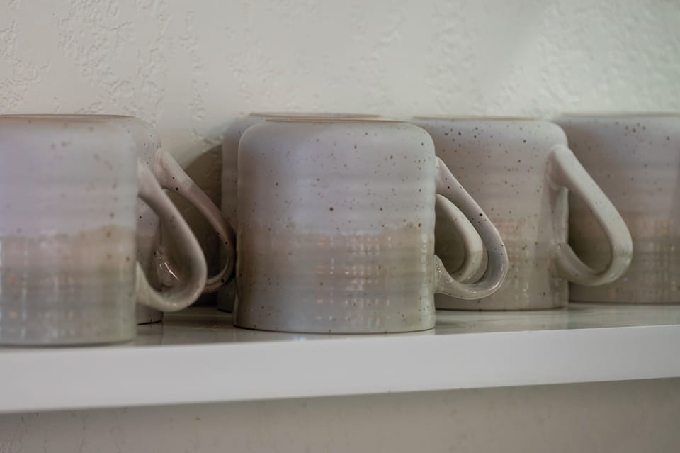 - Handmade style ceramic mugs add charm to your morning routine or evening tea - Neatly stacked on floating shelves for easy access during your stay - Each one has a rustic touch that complements the cozy cabin aesthetic