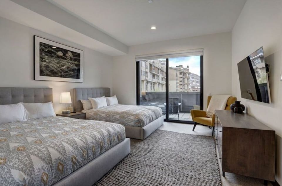 Elegant bedroom featuring two plush beds and a flat-screen TV.
