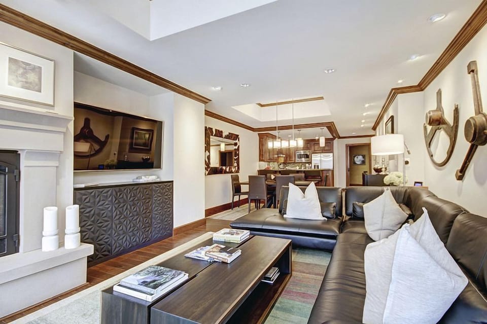 The inviting living area boasts a luxurious leather sofa, warm lighting, and seamless access to the modern kitchen, perfect for relaxation.