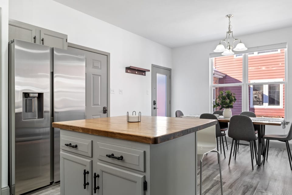 The reverse kitchen view shows the island, refrigerator, dining room, and rear entrance in one connected layout.