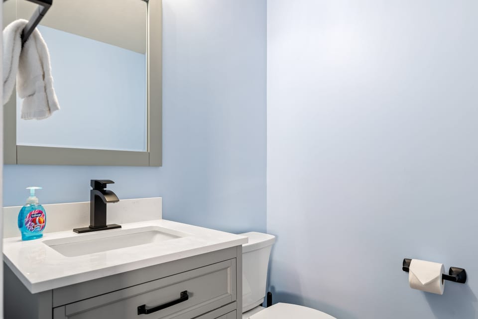 The main-level powder room offers a compact vanity and toilet near the living and dining spaces.