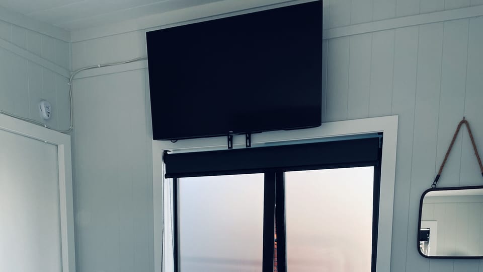 Smart TV above bedroom window with remote.