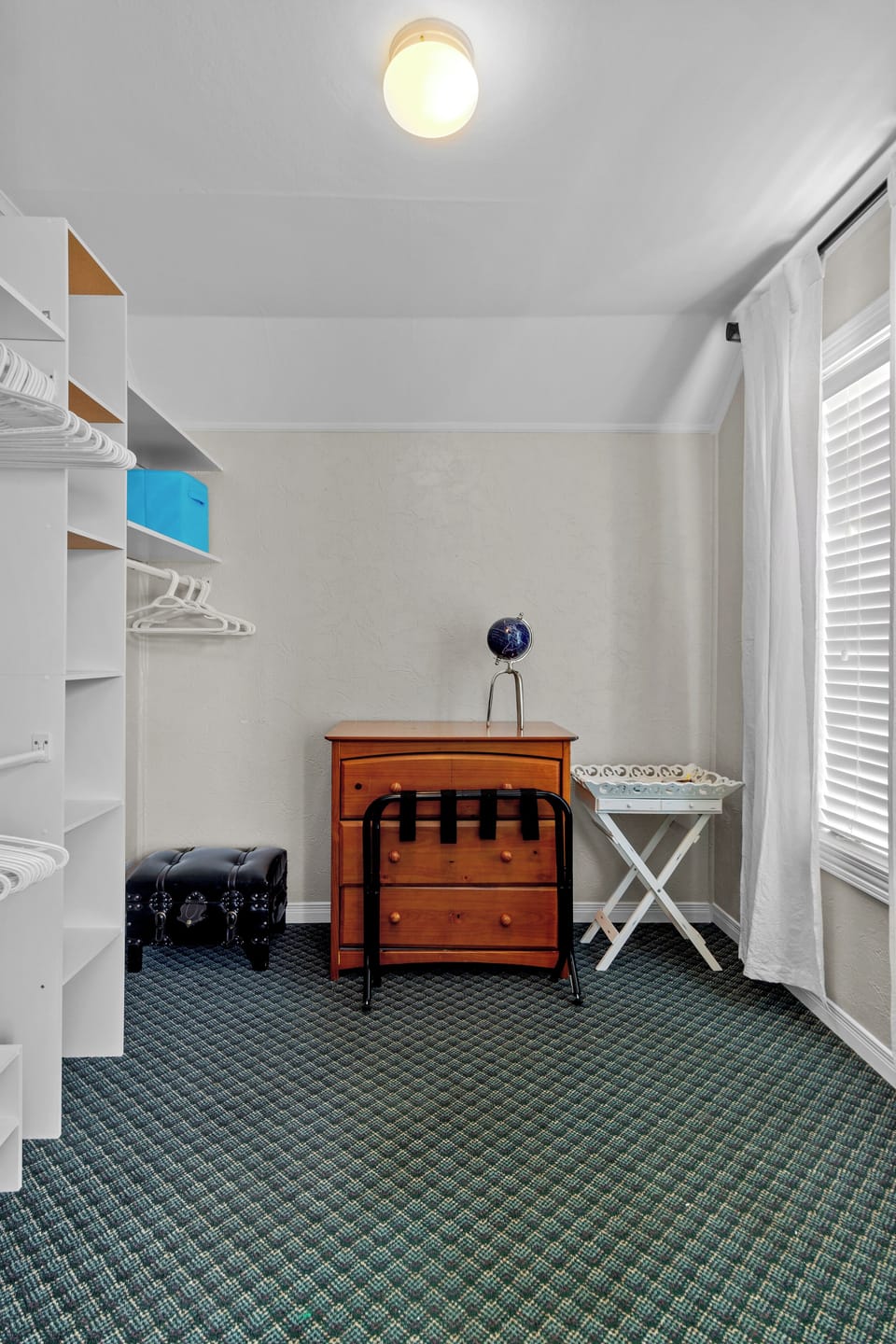 This spacious walk-in closet offers ample shelving and hanging space, perfect for organizing clothes and accessories. The large window lets in plenty of natural light.
