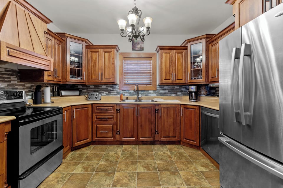 The kitchen is designed for the home chef, featuring stainless steel appliances, ample counter space, and rich wooden cabinetry. The tile flooring and stylish backsplash add a contemporary touch to this functional space.