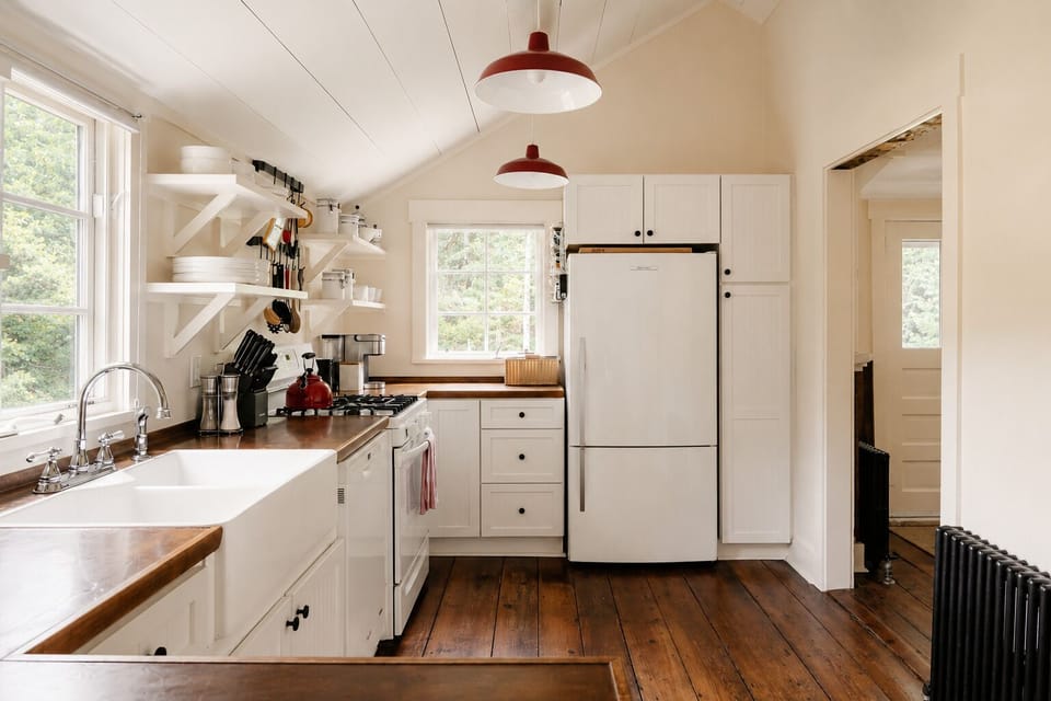 Store leftovers in the fridge and reach the upper cabinets for extra dishes or pantry items. The pendant lights above stay on for cooking at night, with a spice rack right by the stove for seasoning.