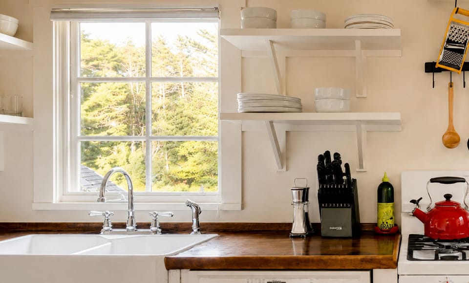 Grab a plate or bowl off the open shelves and use the knife set for prep work at the counter. Wash produce at the farmhouse sink and check the window view of the trees while you work.