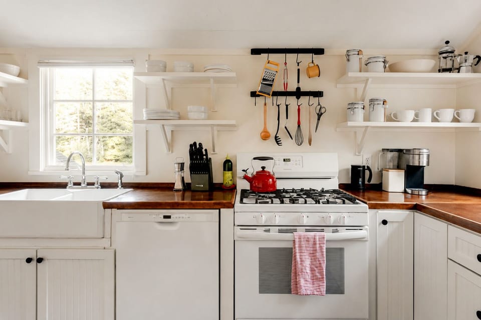 Boil water in the red kettle and cook a full meal on the gas range with the utensils hanging right above it. The dishwasher and farmhouse sink make cleanup easy once you are done in the kitchen.