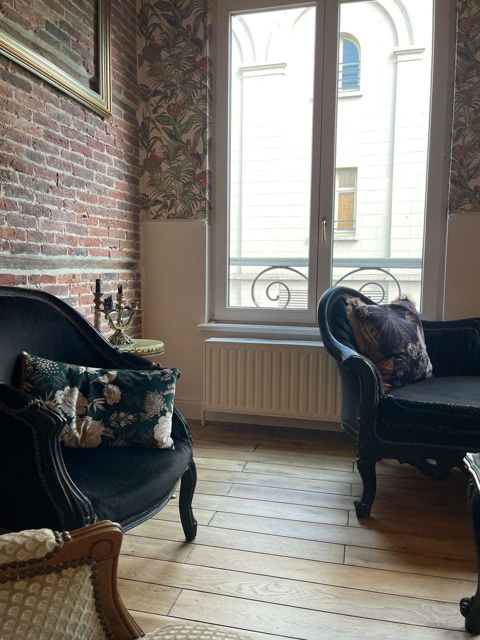 Cosy corner with velvet seating and exposed brick wall in a charming Brussels city center Art Deco flat.