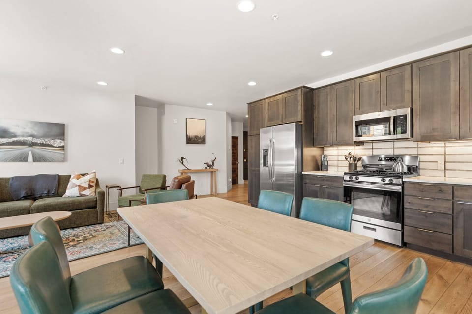 Gather around your spacious dining table with modern seating, perfectly set between your fully equipped kitchen and cozy living area—ideal for family meals and memorable conversations.