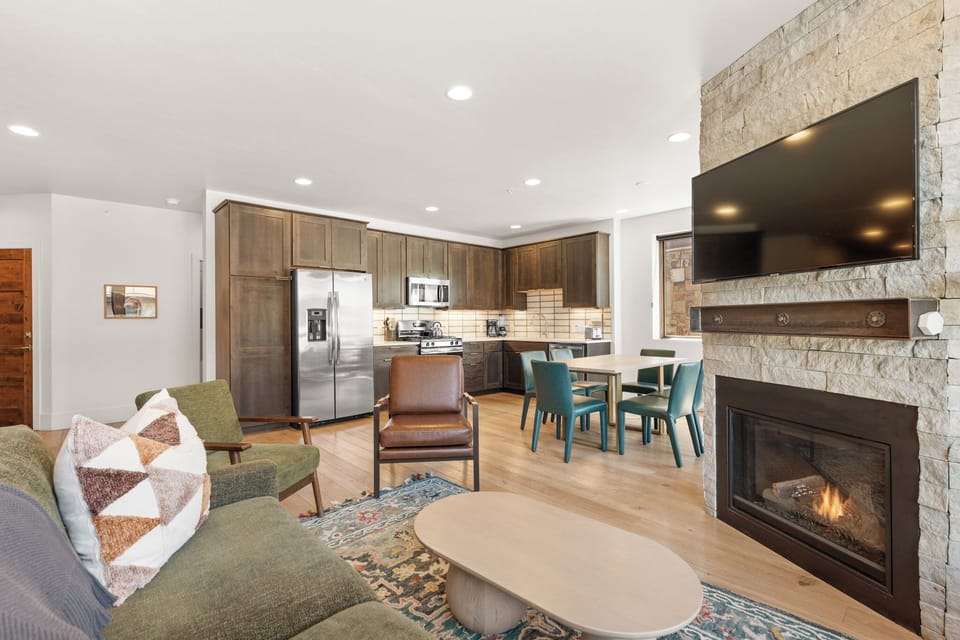 Gather around the cozy fireplace or enjoy meals at your dining table in this open-concept space, where modern design meets mountain charm for your perfect retreat.