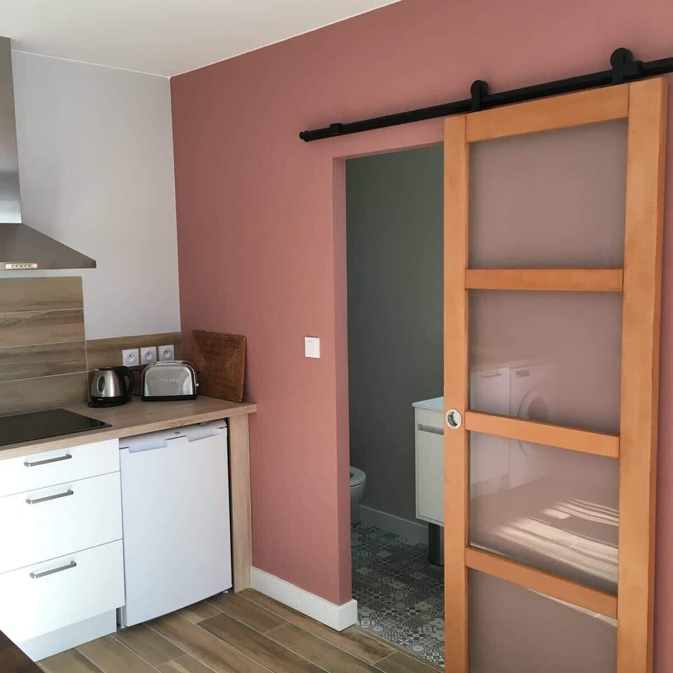 Kitchenette avec meubles blancs, cafetière et porte coulissante en bois