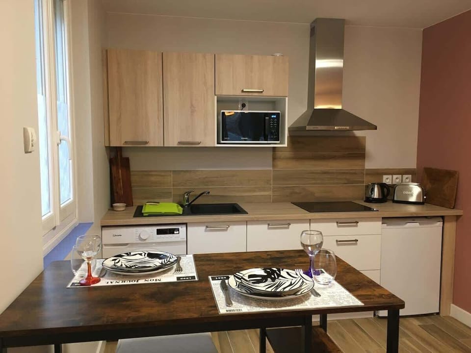 Cuisine équipée avec plaque de cuisson, hotte, plan de travail et vaisselle dressée