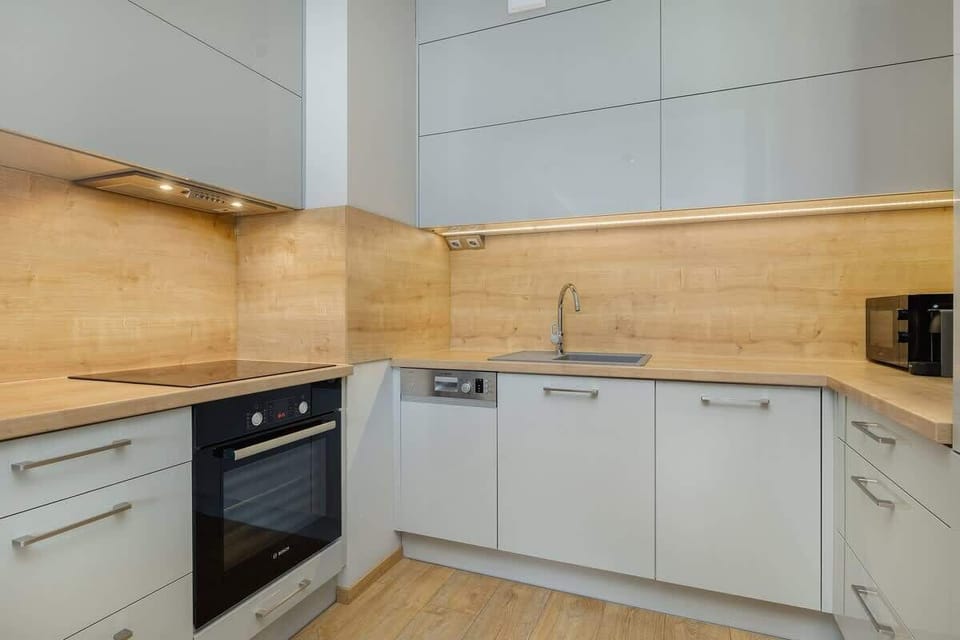 A stylish kitchen with white cabinets and wood finishes. Modern appliances and a spacious counter make cooking effortless.