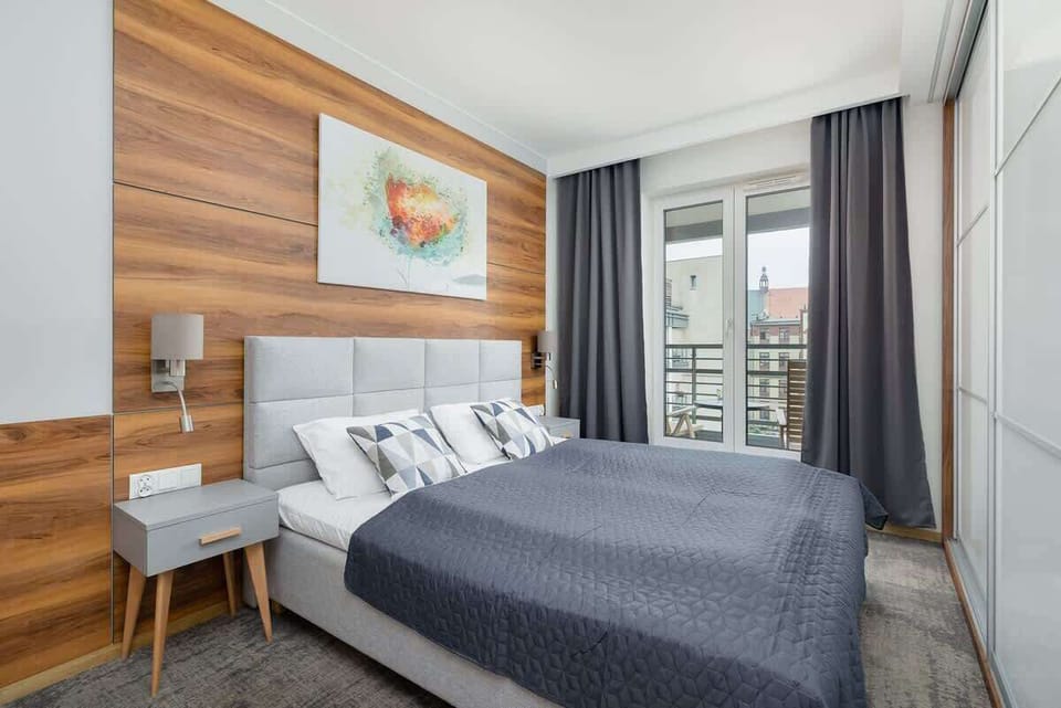 A serene bedroom with a double bed adorned with grey bedding. Wooden panels behind the bed create a warm, contemporary atmosphere.