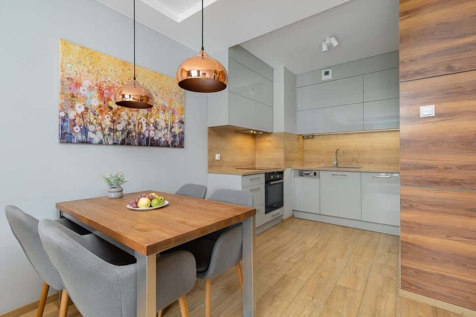 A dining area adjacent to a modern kitchen, perfect for shared meals. Warm lighting and tasteful artwork complete the setting.